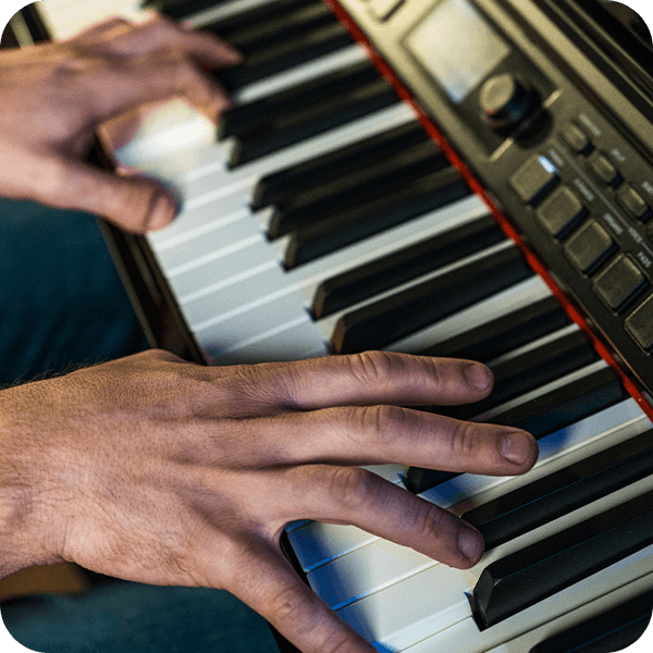 Williams Overture III digital console piano black with pianist hand playing close up.