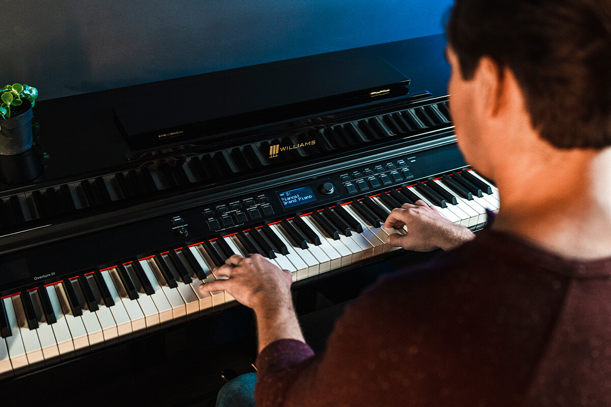Man playing the Williams Overture III digital console piano.
