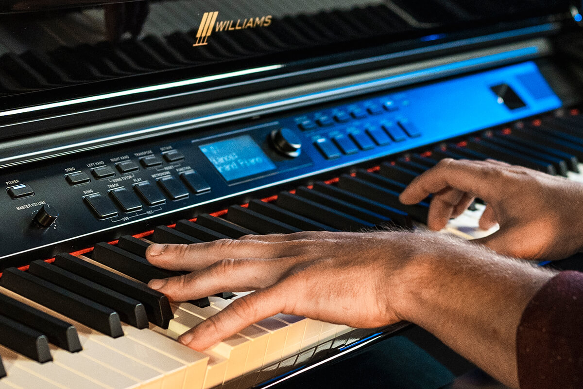 Close of a man hands playing the Williams Overture III digital console piano.