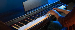 Pianist playing the Williams Rhapsody III digital piano walnut in dark room.